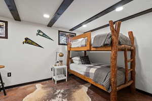 Bedroom with beamed ceiling and concrete floors