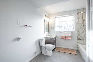 Full bathroom with vanity, a textured ceiling, tile patterned flooring, toilet, and tiled shower / bath