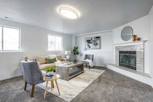 Carpeted living room with a tile fireplace and a textured ceiling