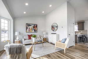 Living room with high vaulted ceiling and light hardwood / wood-style flooring