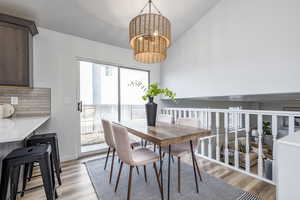 Dining room featuring light hardwood / wood-style floors, lofted ceiling, and a chandelier