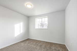 Empty room featuring a textured ceiling and carpet floors