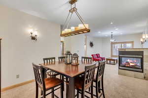 Dining space with a tiled fireplace and light carpet