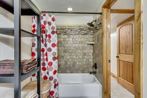 Bathroom featuring tile patterned flooring, shower / bath combination with curtain, and a textured ceiling