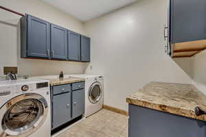 Laundry area featuring light tile patterned flooring, cabinets, and washing machine and dryer