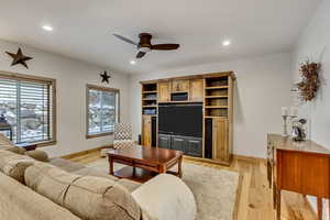 Living room with light hardwood / wood-style floors and ceiling fan