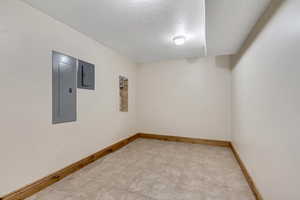 Spare room with electric panel and a textured ceiling