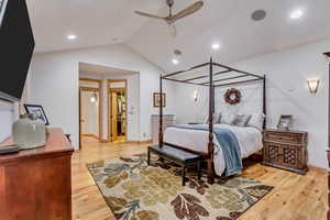 Bedroom featuring light wood-type flooring, vaulted ceiling, ceiling fan, a spacious closet, and a closet