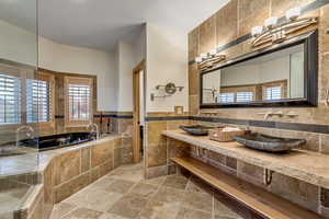 Bathroom with sink, a relaxing tiled tub, breakfast area, and tile walls