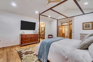 Bedroom with connected bathroom, ceiling fan, lofted ceiling, and light wood-type flooring