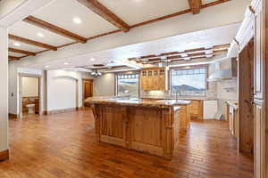 Kitchen featuring light stone countertops, wood-type flooring, a center island, and a kitchen breakfast bar