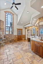 Kitchen featuring tile walls, light stone counters, ceiling fan, and sink