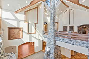 Interior space with beam ceiling, high vaulted ceiling, and light hardwood / wood-style flooring