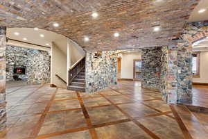 Unfurnished living room featuring a fireplace, a healthy amount of sunlight, and brick ceiling