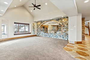 Unfurnished living room featuring carpet, ceiling fan, and high vaulted ceiling