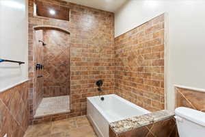 Bathroom with tiled shower / bath combo and toilet