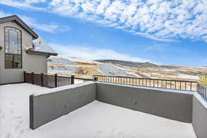 Snow covered patio featuring a mountain view and a balcony