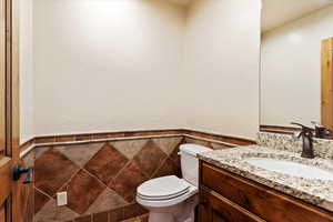 Bathroom featuring vanity, toilet, and tile walls