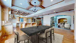 Dining area featuring a chandelier, beam ceiling, light hardwood / wood-style flooring, and coffered ceiling