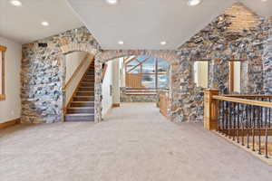 Unfurnished living room with light carpet and vaulted ceiling