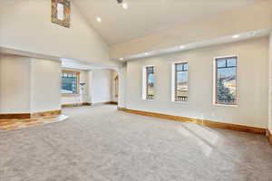 Unfurnished living room with carpet flooring and high vaulted ceiling