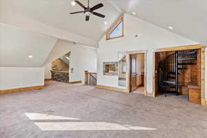 Unfurnished living room featuring ceiling fan, high vaulted ceiling, and light colored carpet