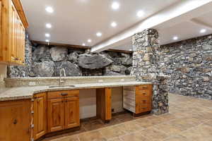 Kitchen with light stone counters, sink, and beamed ceiling