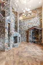 Unfurnished living room with a notable chandelier and a stone fireplace