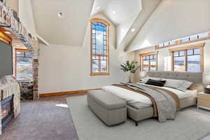 Carpeted bedroom with a fireplace and high vaulted ceiling