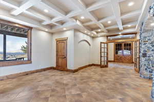 Spare room featuring beam ceiling, french doors, and coffered ceiling