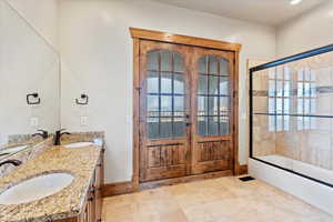 Bathroom with vanity and bath / shower combo with glass door