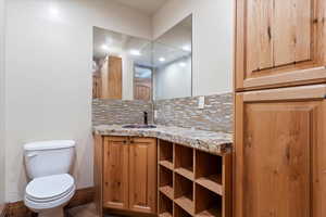 Bathroom featuring backsplash, vanity, and toilet