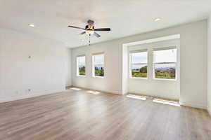 Empty room featuring ceiling fan, a textured ceiling, and light hardwood / wood-style flooring