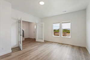 Unfurnished bedroom featuring french doors and light hardwood / wood-style flooring