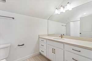 Bathroom with vanity, a textured ceiling, vaulted ceiling, wood-type flooring, and toilet