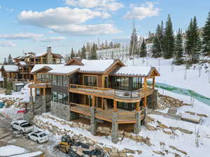 Snow covered back of property with a balcony