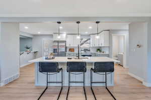 Kitchen featuring a center island, white cabinetry, hanging light fixtures, and appliances with stainless steel finishes