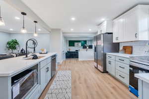 Kitchen featuring white cabinetry, sink, stainless steel appliances, and light hardwood / wood-style floors