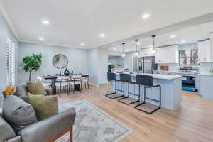 Living room featuring light wood-type flooring and ornamental molding