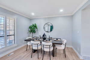 Dining area with ornamental molding and light wood-type flooring