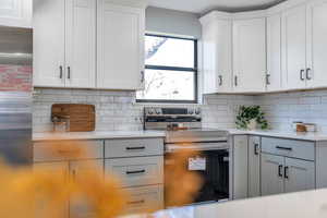 Kitchen with white cabinetry, appliances with stainless steel finishes, and tasteful backsplash