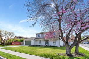 Traditional-style house with fence, an attached garage, driveway, and a front yard