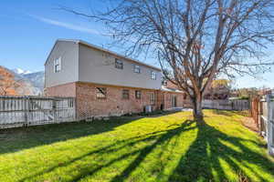 Back of property featuring a mountain view, a yard, and cooling unit