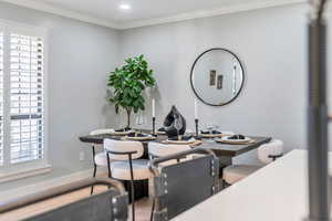 Dining space with hardwood / wood-style floors, a healthy amount of sunlight, and crown molding