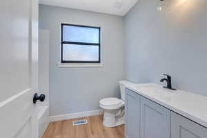 Full bathroom featuring hardwood / wood-style floors, vanity, shower / bathtub combination, and toilet