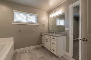 Bathroom with a tub, vanity, and a textured ceiling