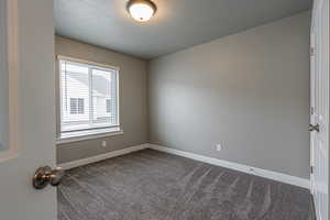 Carpeted spare room with a textured ceiling