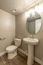 Bathroom featuring sink, toilet, a textured ceiling, and hardwood / wood-style flooring