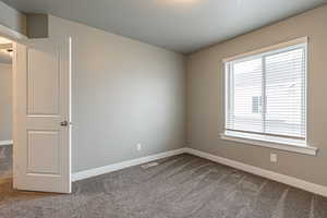 Carpeted spare room with a textured ceiling and a wealth of natural light