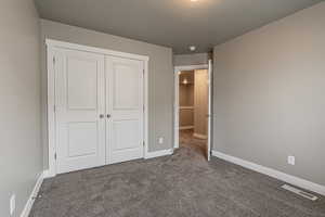 Unfurnished bedroom with dark carpet, a textured ceiling, and a closet